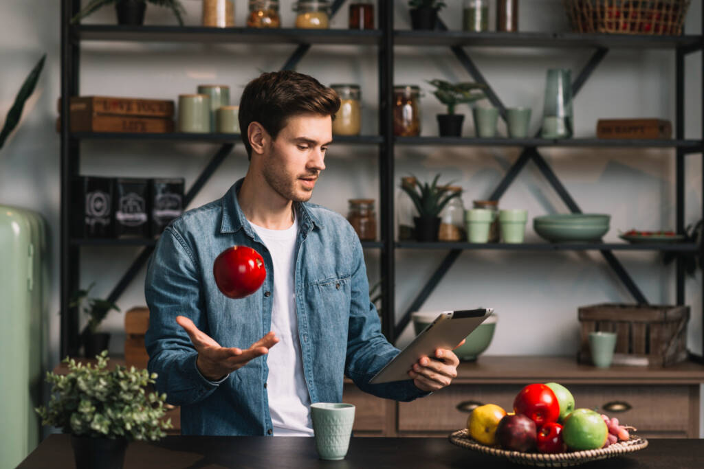 Homem com uma maça na mão e um tablet na outra mão