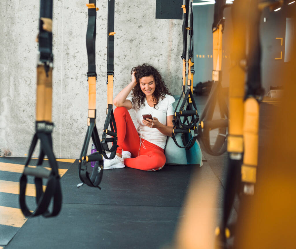 Mulher descansa dentro da academia e olha para o celular