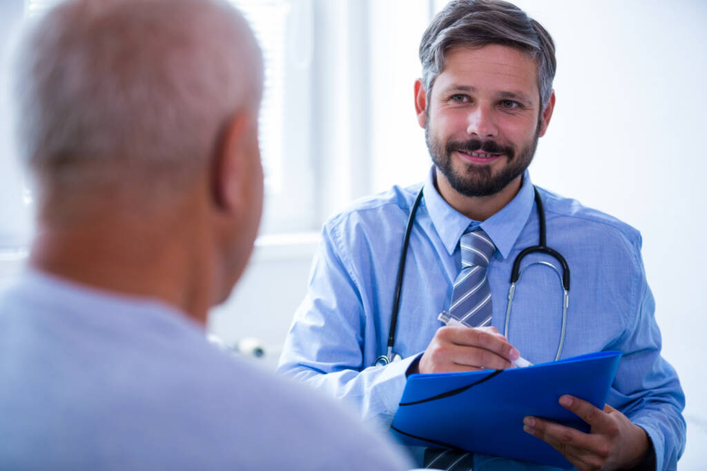 Homem idoso conversa com médico que faz anotações