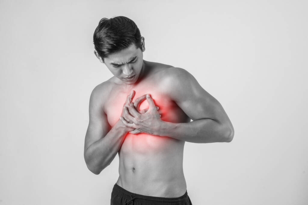 foto em preto e branco de pessoa sem camisa com a mão no peito e expressão de dor