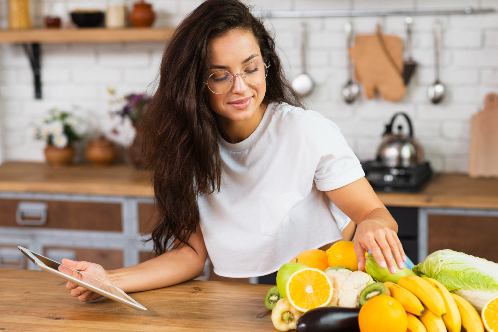 mulher em cozinha seleciona fruta e legumes que estão sobre um balcão