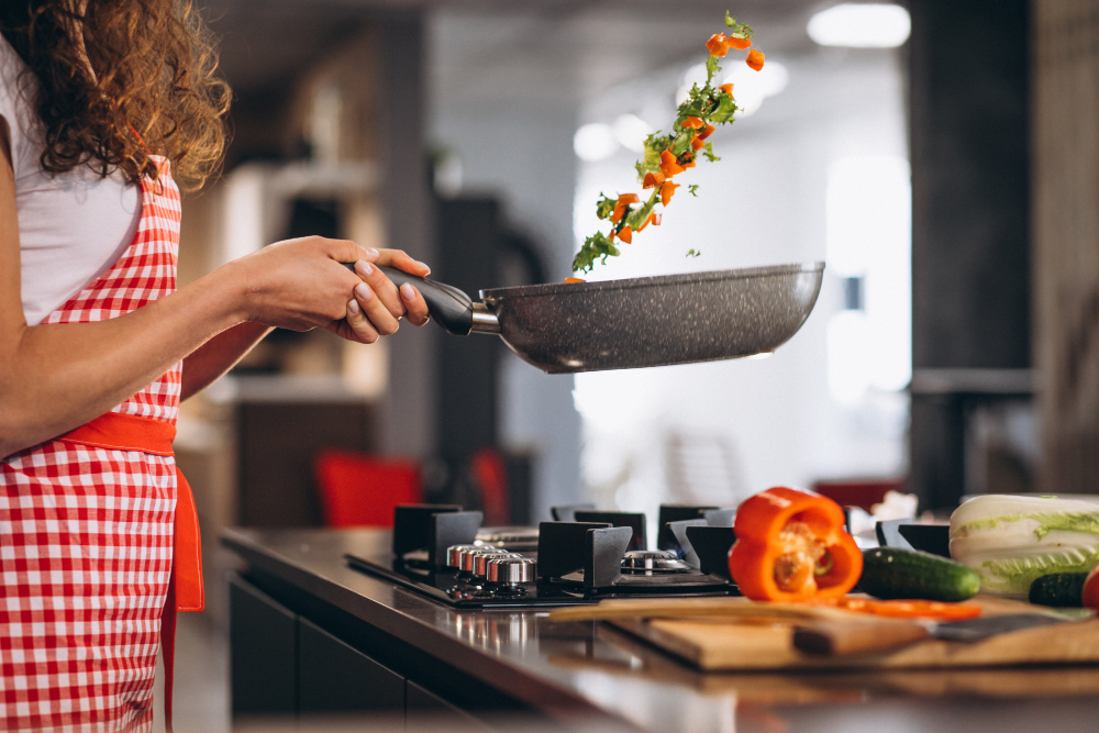 mulher cozinha legumes em uma frigideira